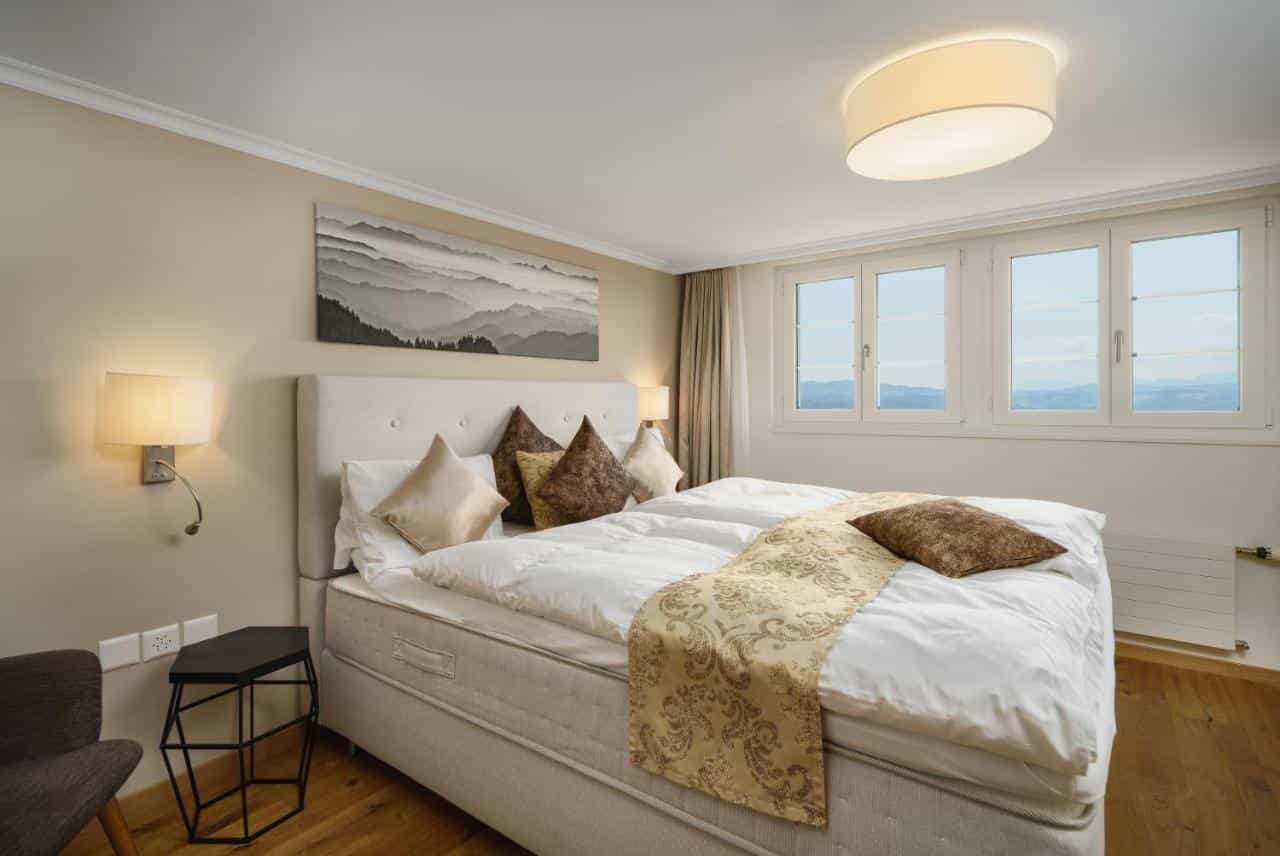 Boutique hotel room with large bed, mountain art, and windows showing distant hills.
