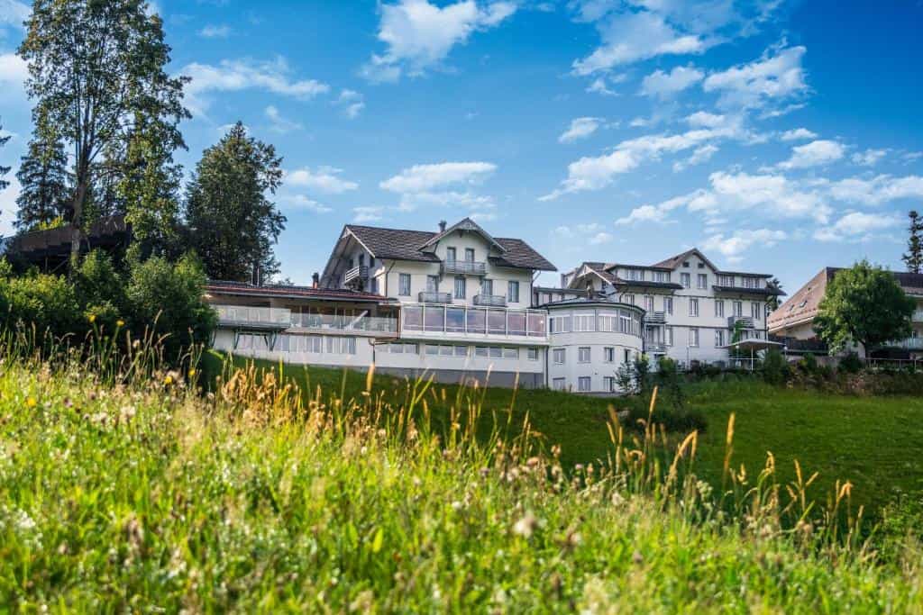 Boutique Hotel Moosegg building on grassy hillside under blue sky with clouds