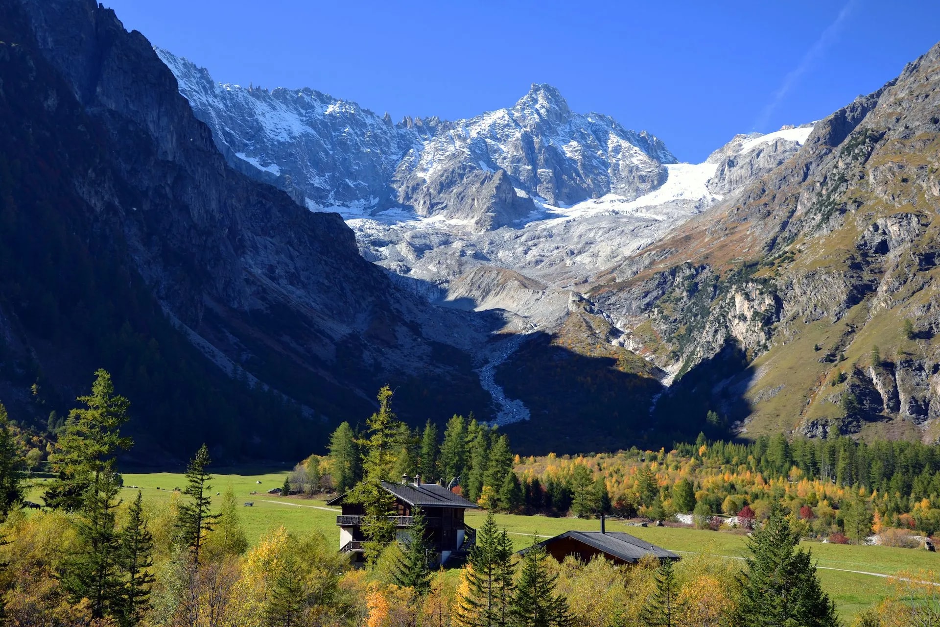 Alpine village of La Fouly in Val Ferret with snow-capped mountains and autumn foliage.