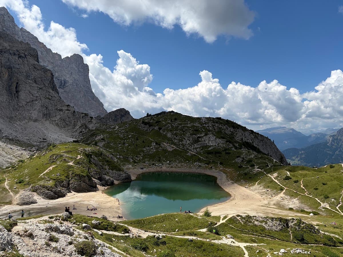 Alpine mountain lake with green water and rocky peaks under a blue sky with clouds